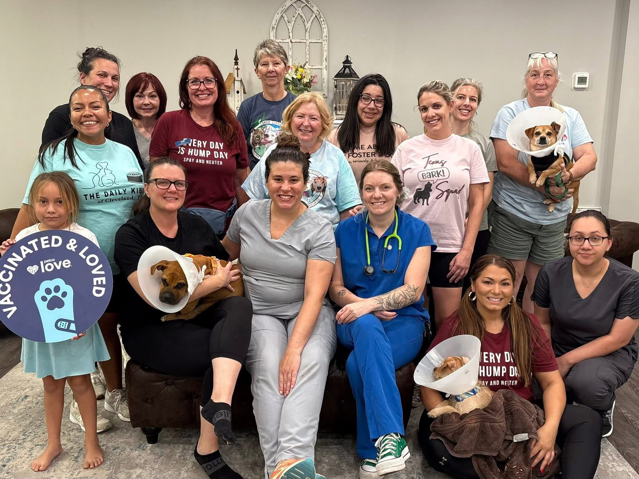 A large group of rescue caregivers posing indoors with dogs