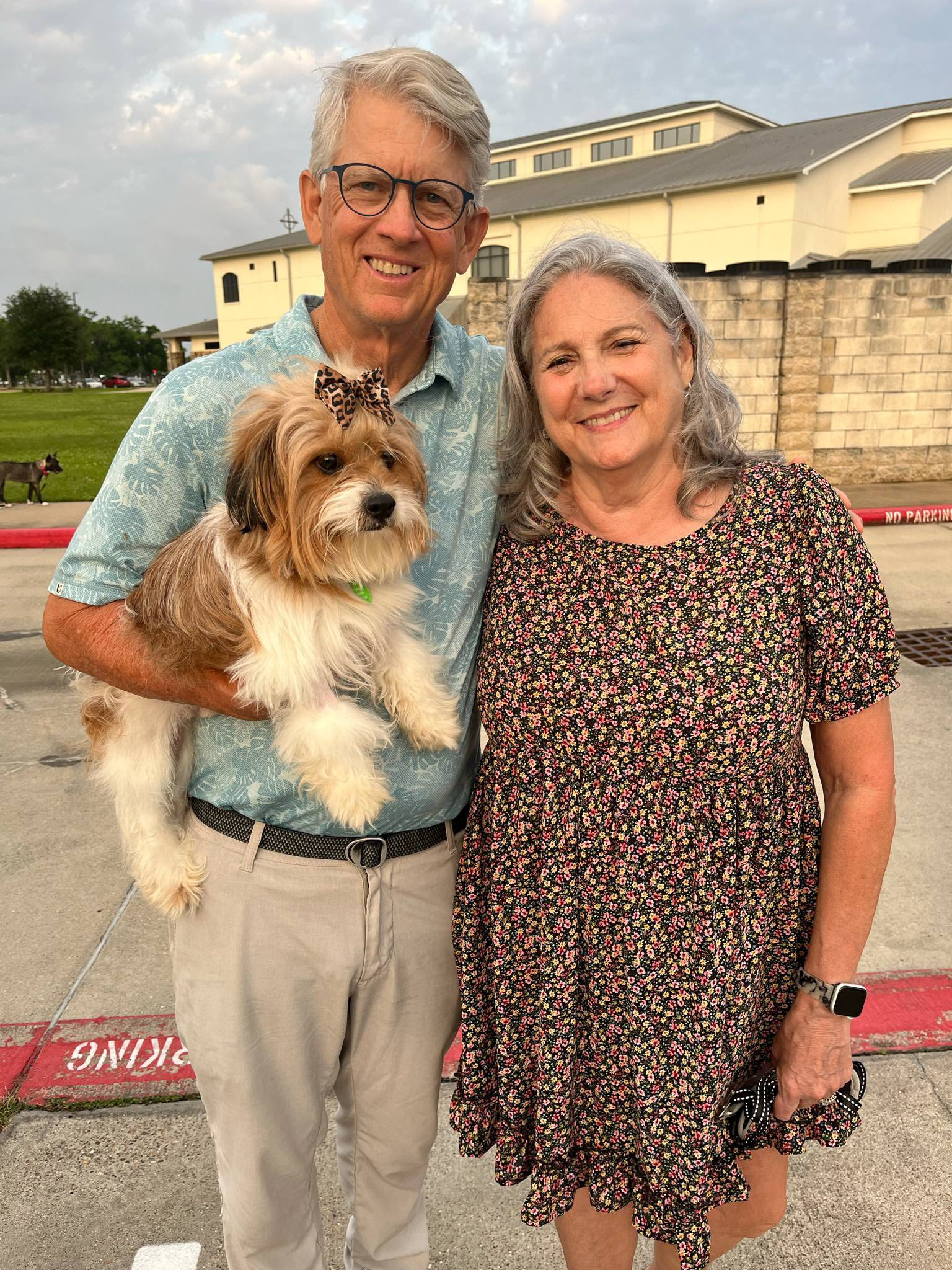An older couple smiling with a shaggy dog outdoors